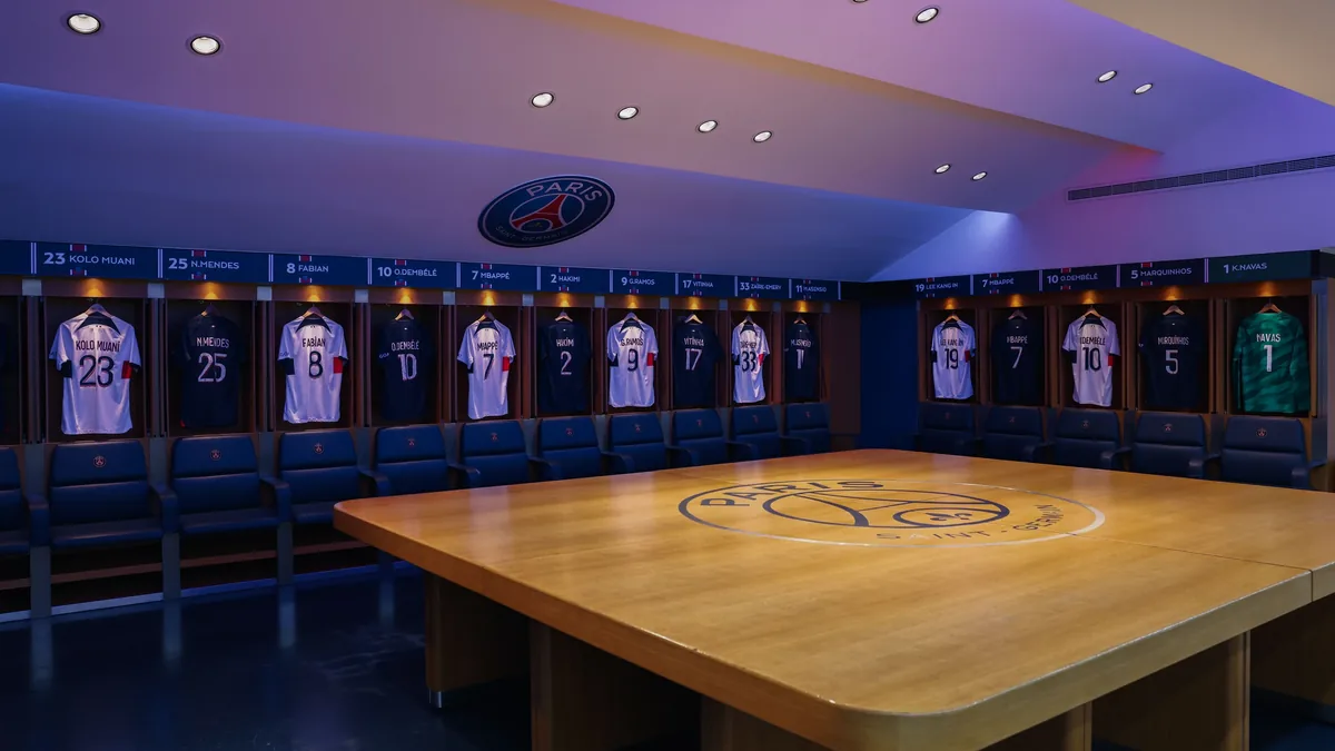 Vestiário de estádio com camisas numeradas penduradas antes do jogo