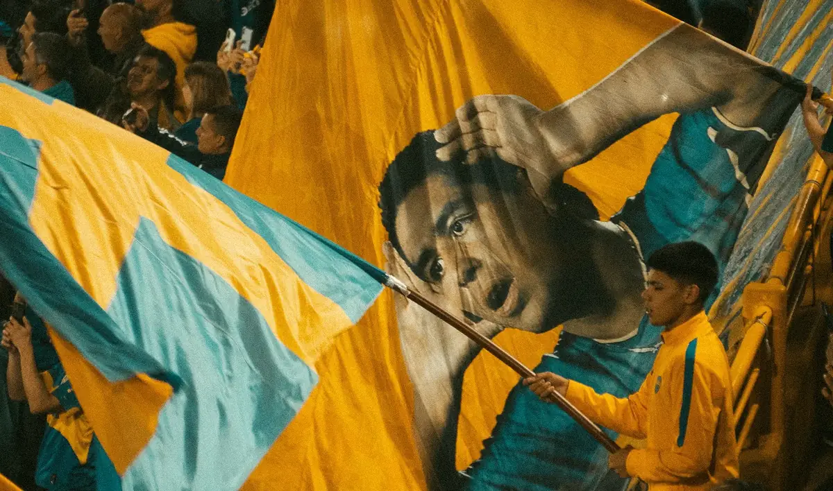 Torcida erguendo bandeirões azuis e amarelos na arquibancada